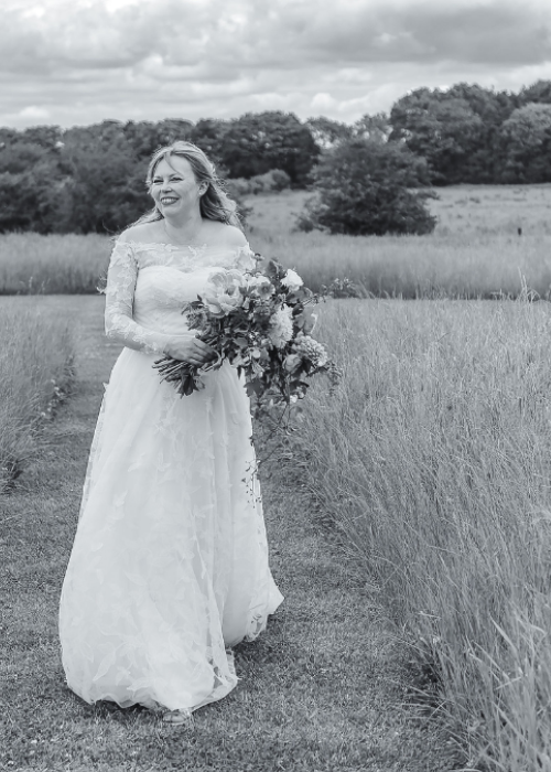 black and white photography of bride walking in a feild