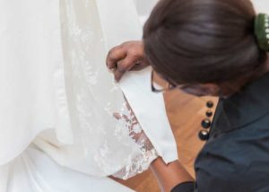 wedding dressmaker hand sewing a lace wedding dress