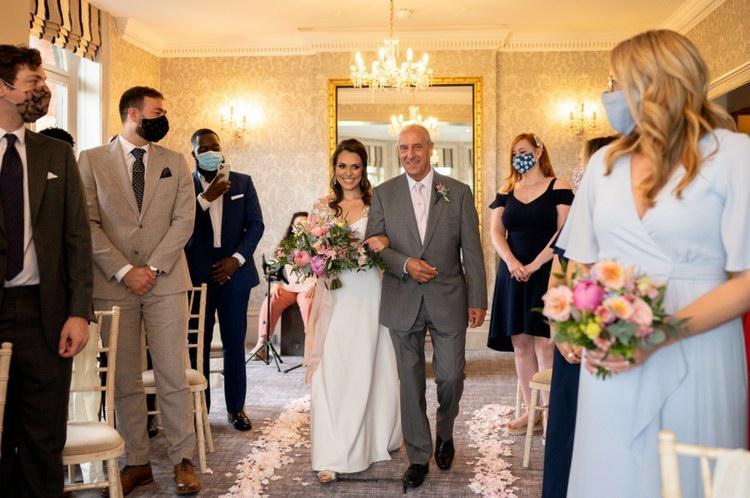 petite bride walking down aisle in proportion-corrected wedding dress